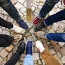 Circle of sneakers on cobblestone pavement representing diversity and urban fashion.